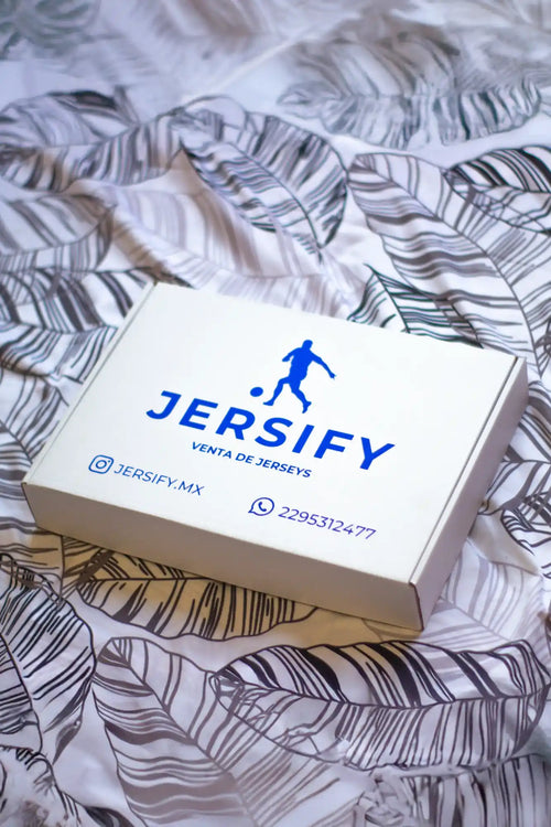 Caja blanca con un logo azul de ‘JERSIFY’ y información de contacto de redes sociales.